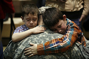 two boys hug soldier dad
